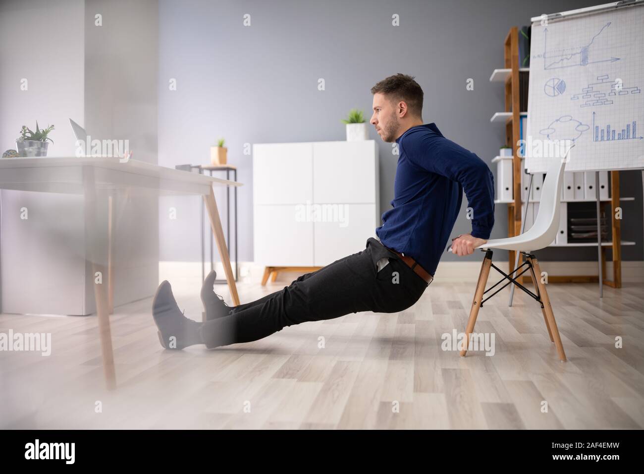 Side View Of A Young Woman Doing Stretching Exercise In Office Stock Photo