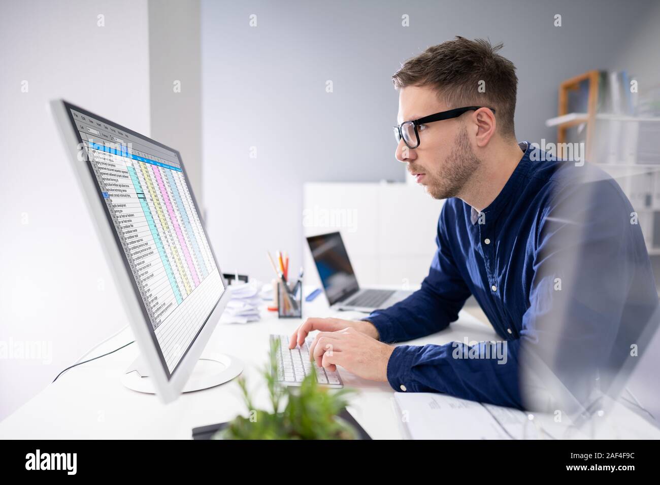 Side View Of Businessman's Hand Analyzing Data On Computer Over Desk Stock Photo