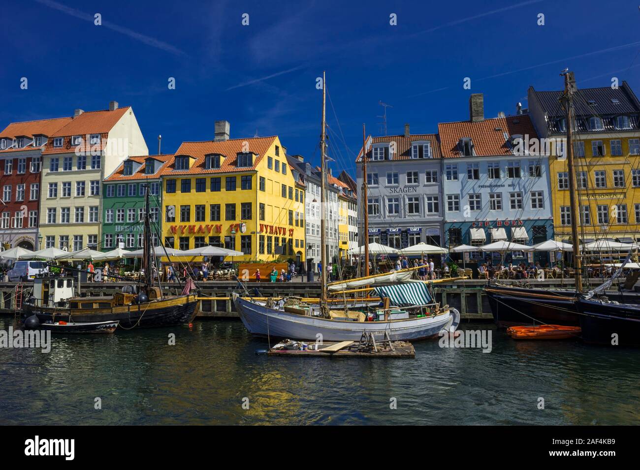 Small sailing boats on the Nyhavn canal in front of bright coloured buildings in Copenhagen, Denmark Stock Photo