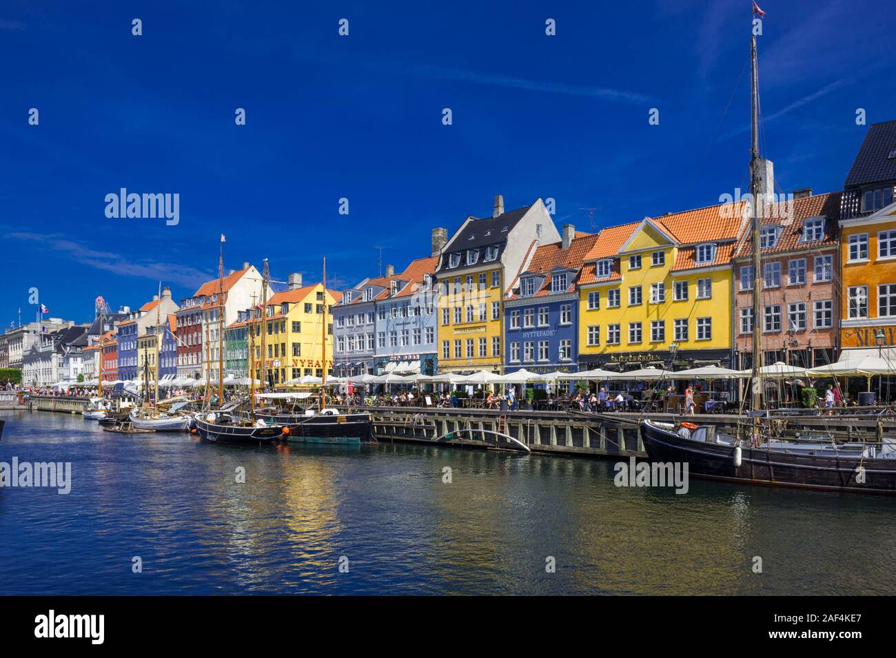 Small sailing boats on the Nyhavn canal in front of bright coloured buildings in Copenhagen, Denmark Stock Photo