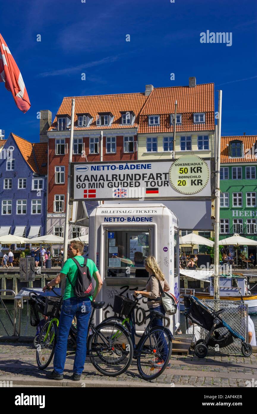 Two cyclists by the canal cruise ticket kiosk by the waterfront in Copenhagen, Denmark Stock Photo