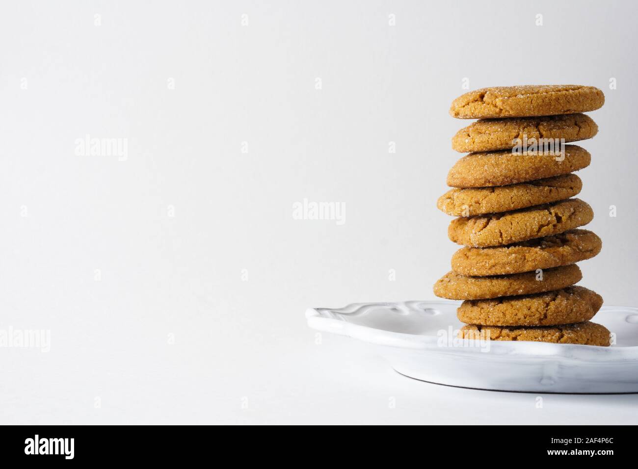 A pile of gingerbread cookies on a white plate and white background with copy space to the left Stock Photo