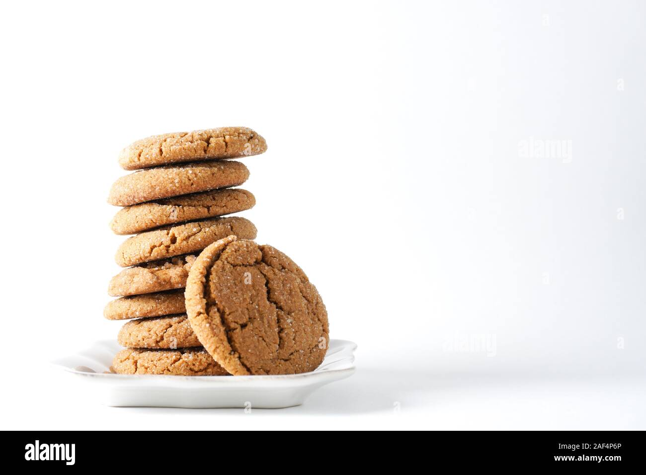 A gingerbread cookie leans on a stack on cookies on a white plate isolated on a white background; copy space on right Stock Photo