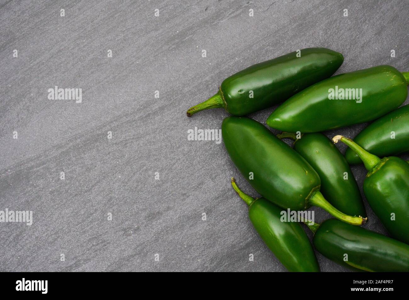 A pile of spicy green jalapenos on a gray slate background with copy space; food preparation Stock Photo