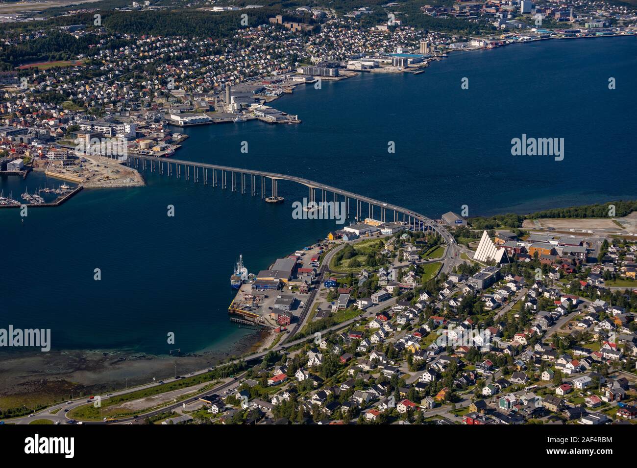 TROMSØ, NORWAY - Aerial view Tromsø Bridge, crossing Tromsøysundet strait from Tromsøya island, left, to Tramsdale. Arctic Cathedral, right.. Stock Photo