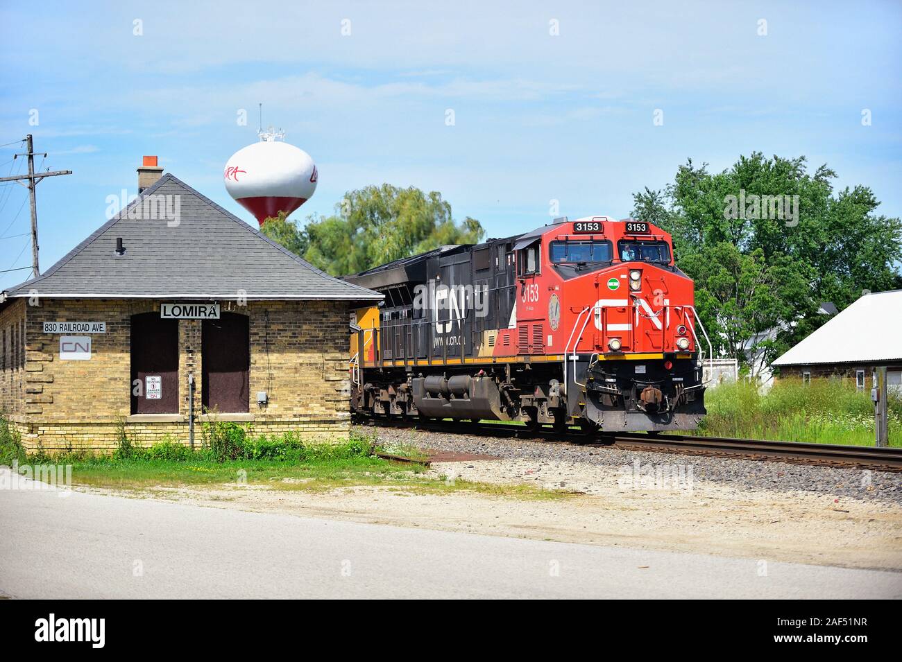 Lomira, Wisconsin, USA. The lead locomotive of three units heads a Canadian National Railway freight train rolling through a small town. Stock Photo