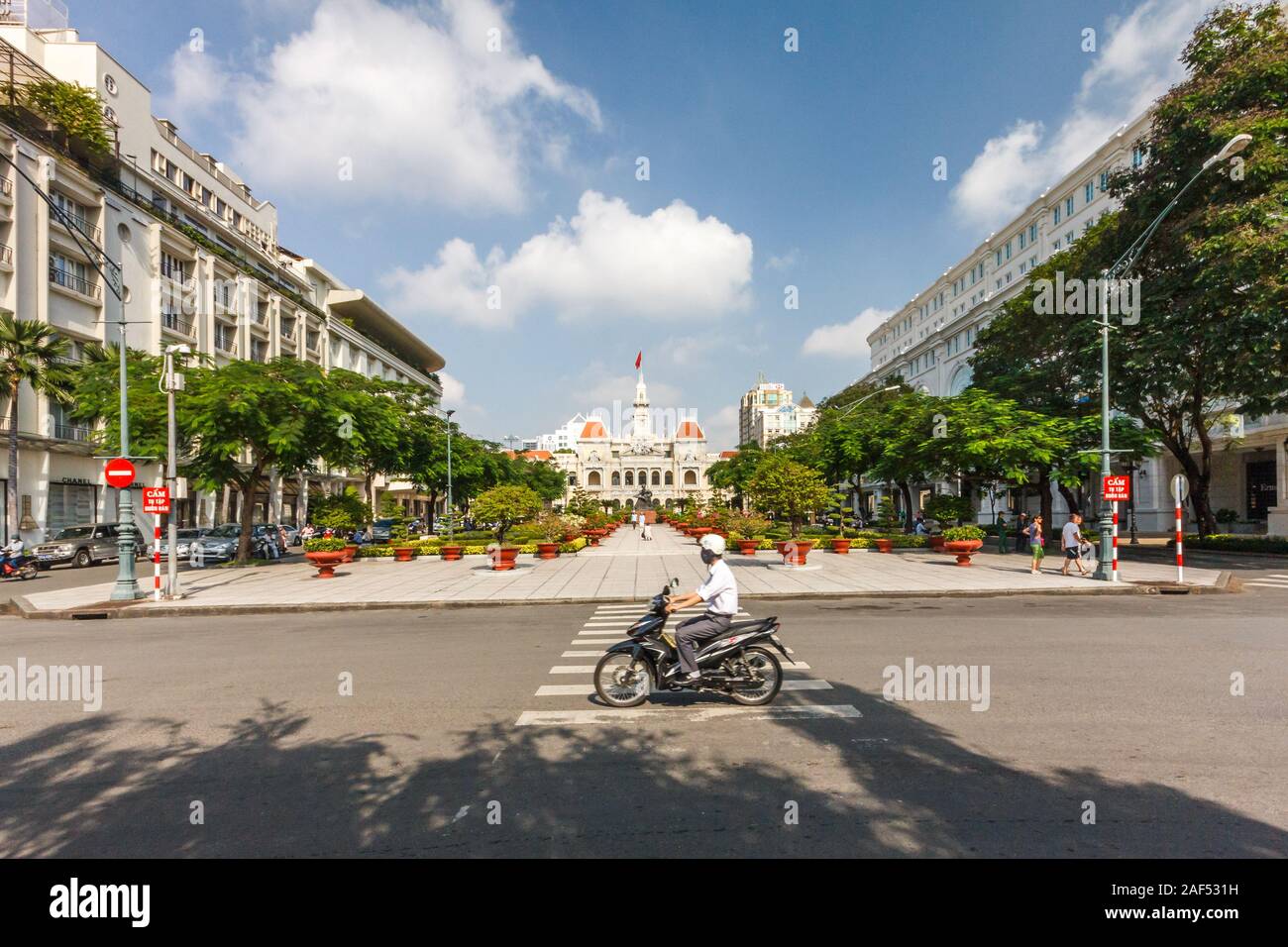 Ho Chi Minh City, Vietnam - October 30th 2013: A motorcyclist rides along the road. In the background is the Peoples Committee Building. Stock Photo