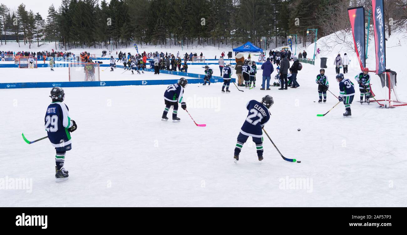 Youngsters playing ice hockey on an exterior rink. Centre de la Nature, Laval, province of Quebec, Canada. Stock Photo