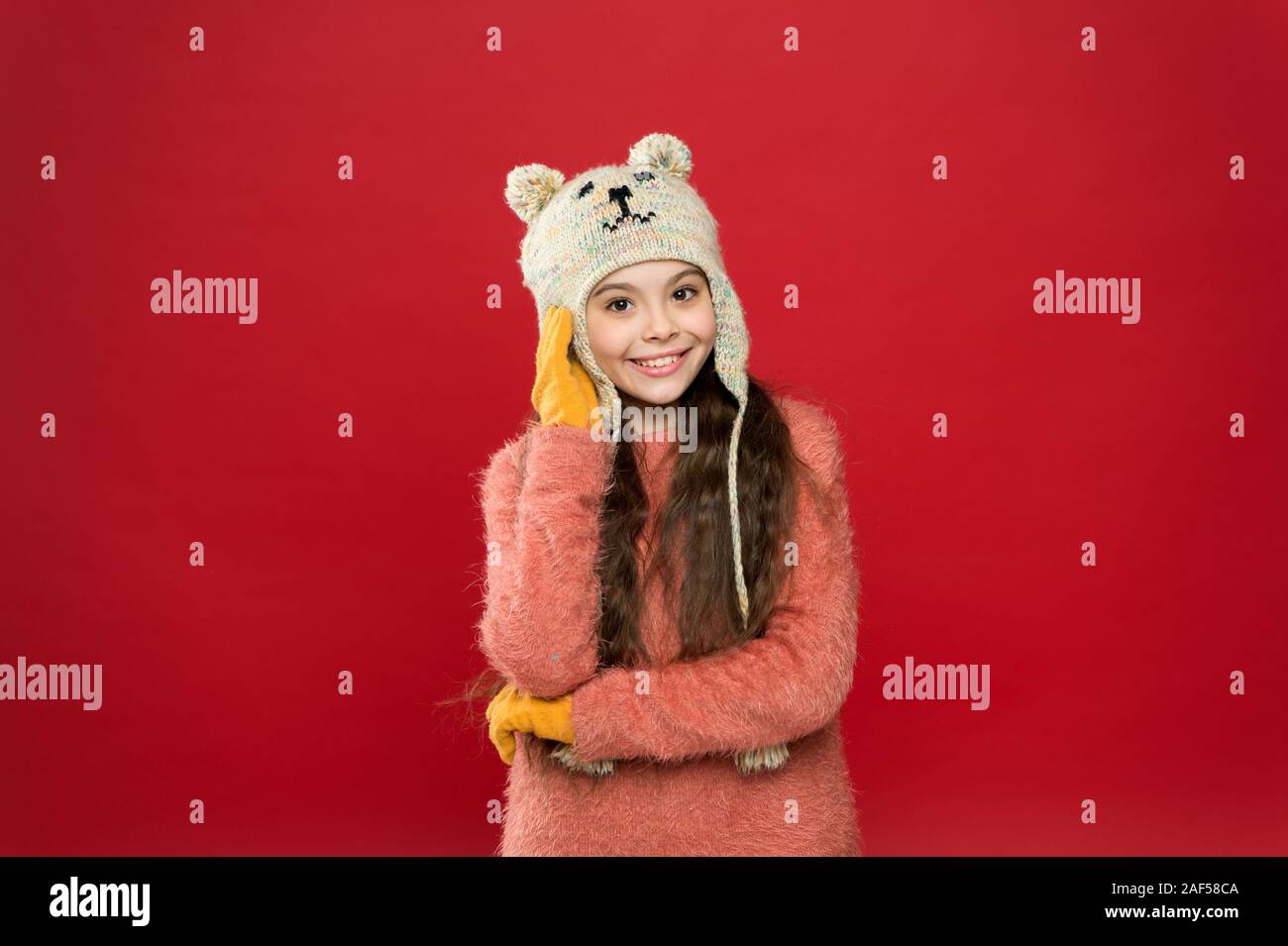 Teddy bear. Being cute bear. Winter outfit. Little kid wear knitted hat. Stay warm. Little girl winter fashion accessory. Small child long hair wear hat red background. Cute model enjoy winter style Teddy bear. Being cute bear. Winter outfit. Little kid wear knitted hat. Stay warm. Little girl winter fashion accessory. Small child long hair wear hat red background. Cute model enjoy winter style