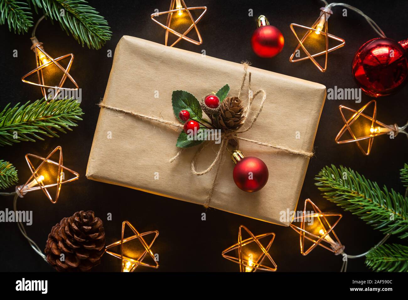 Holiday Christmas card background with festive decoration ball, stars, snowflakes, gift box, pine cones on a black background from Flat lay, top view. Stock Photo