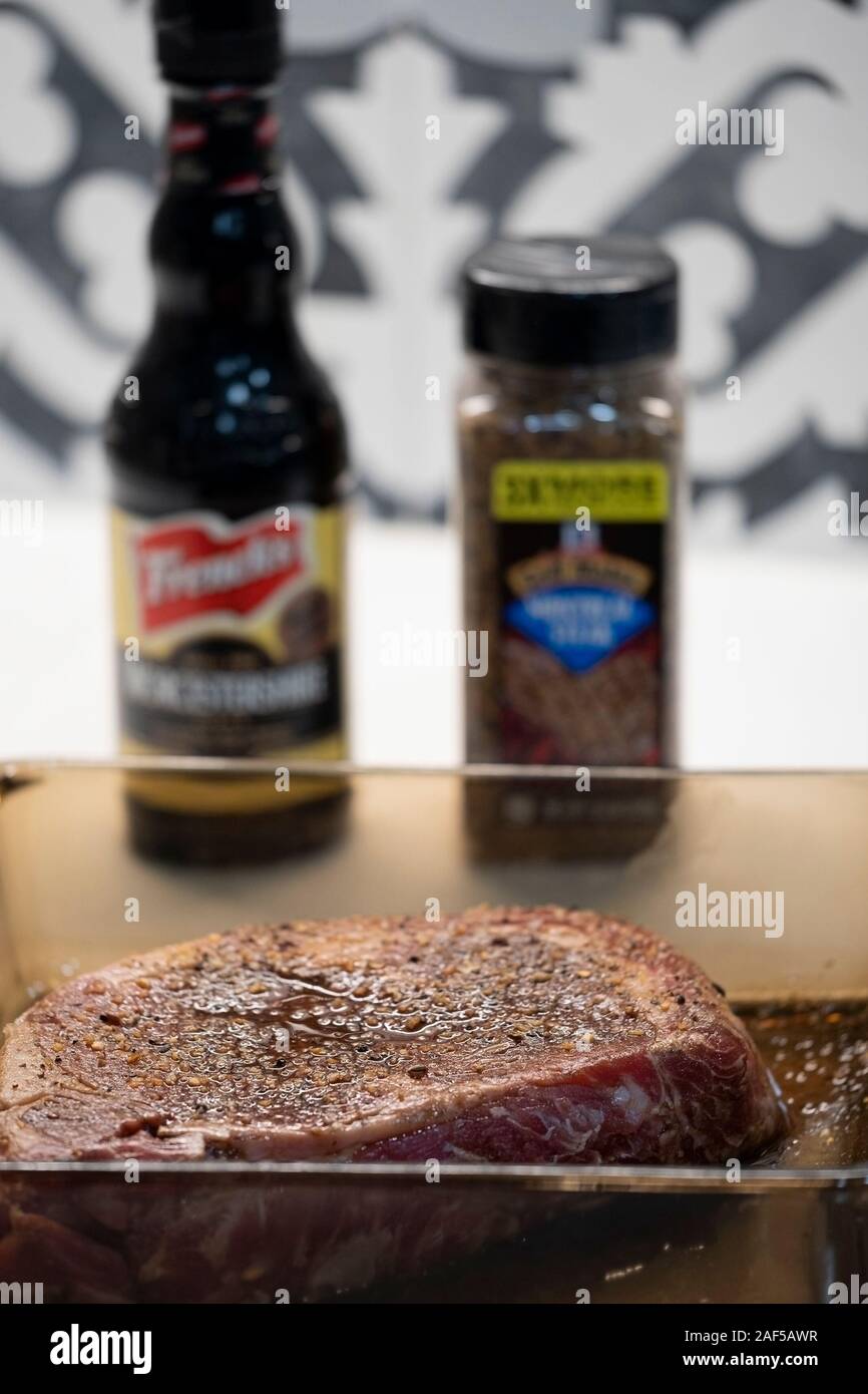 A raw rib eye steak marinating in Worcestershire sauce and dry steak
