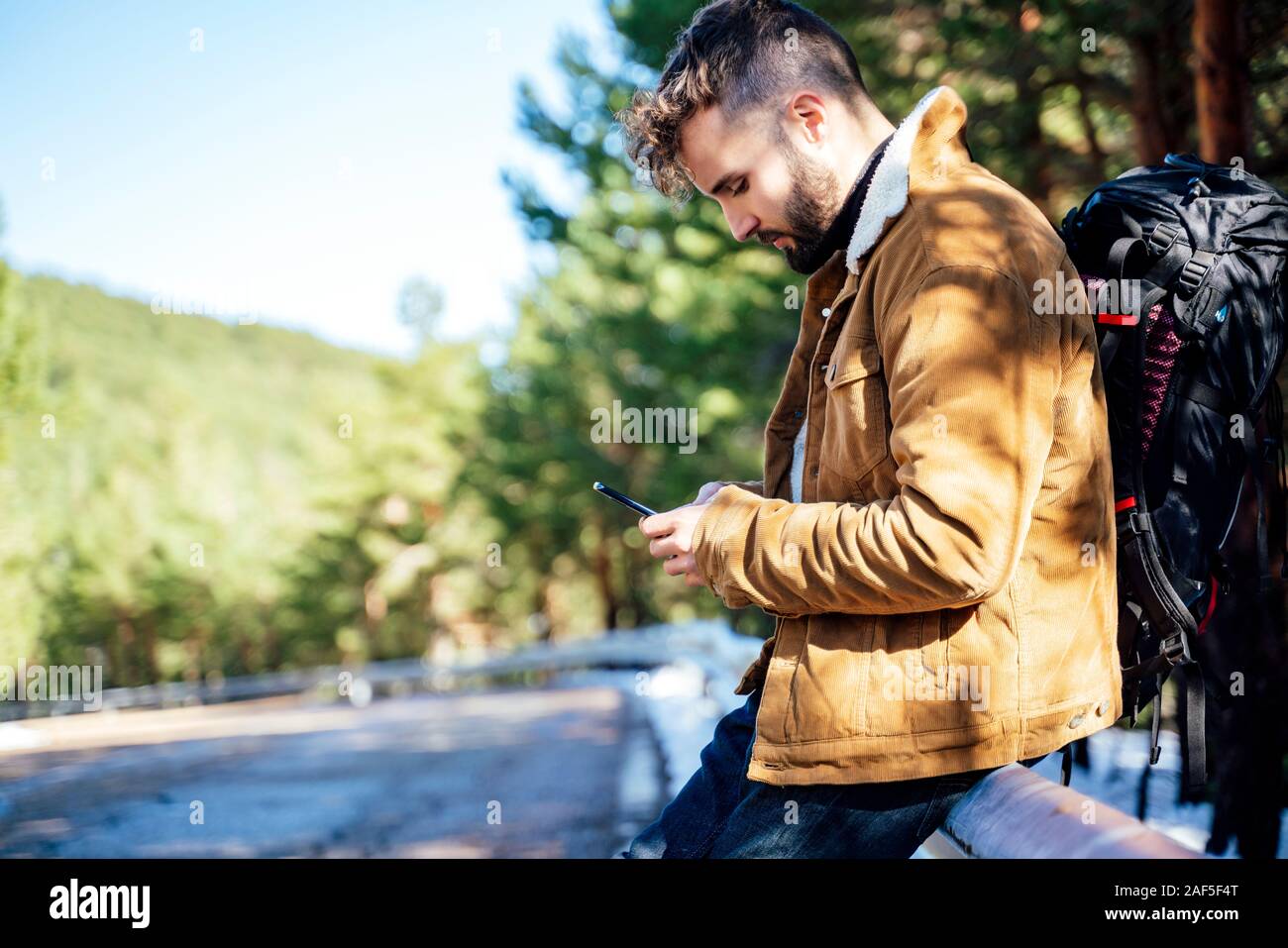 Tourist in the mountains doing auto stop with his cellphone Stock Photo