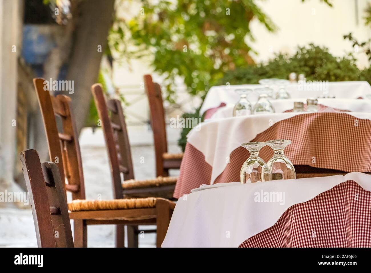 Wooden chairs and table with glasses at a Greek tavern - restaurant in Plaka, Athens Stock Photo