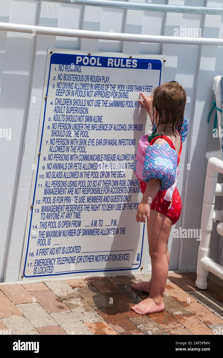 Avon, Outer Banks, North Carolina.  Two-year-old Girl Examining Swimming Pool Rules. (Model Released) Stock Photo