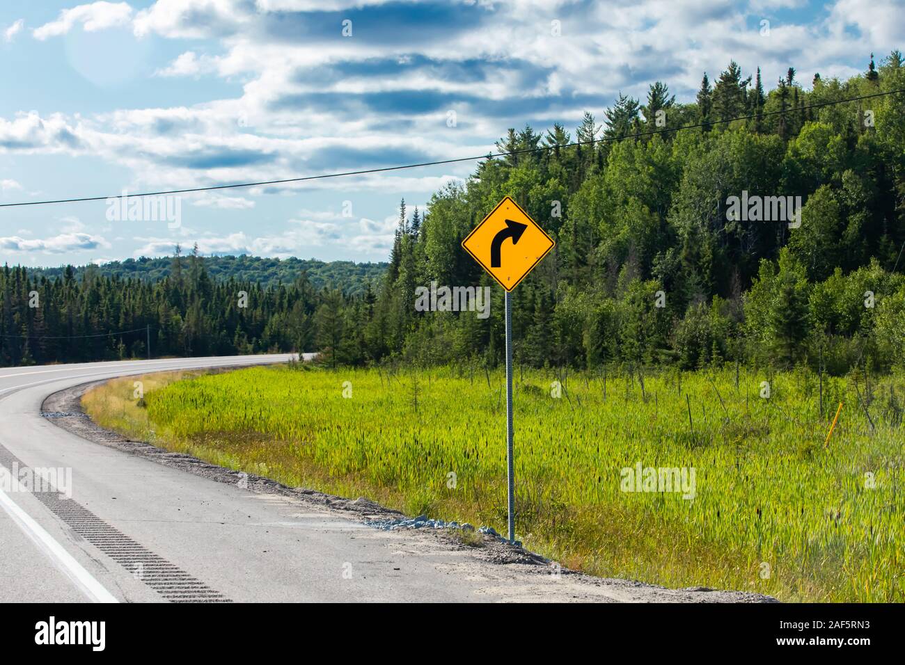 Warning For A Curve To The Right, Slight Bend Or Curve In The Road Ahead,  Warning Road Signs, In Selective Focus View With Forest Trees Background  Stock Photo, Picture and Royalty Free