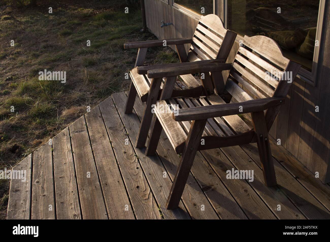 Two wood chairs on a deck outside Stock Photo - Alamy