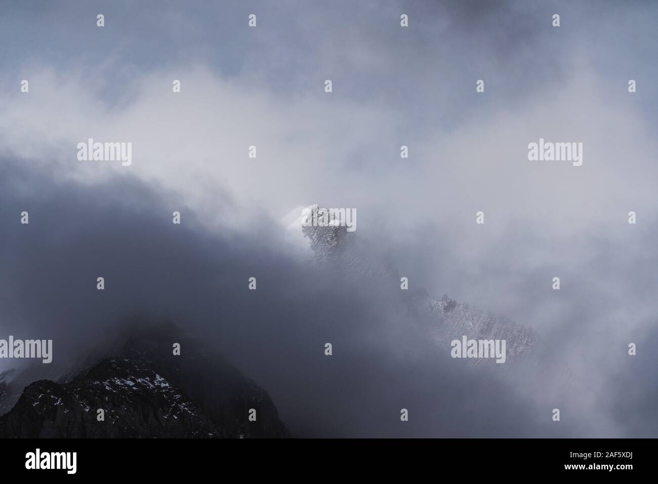 Snow mountain peak behind clouds Stock Photo