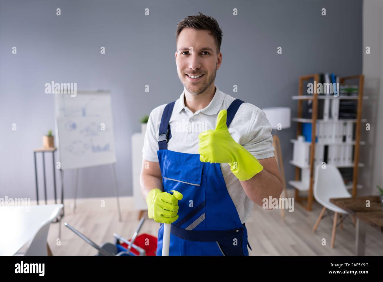 Full Length Portrait Of Happy Male Worker With Broom Cleaning Office Stock Photo