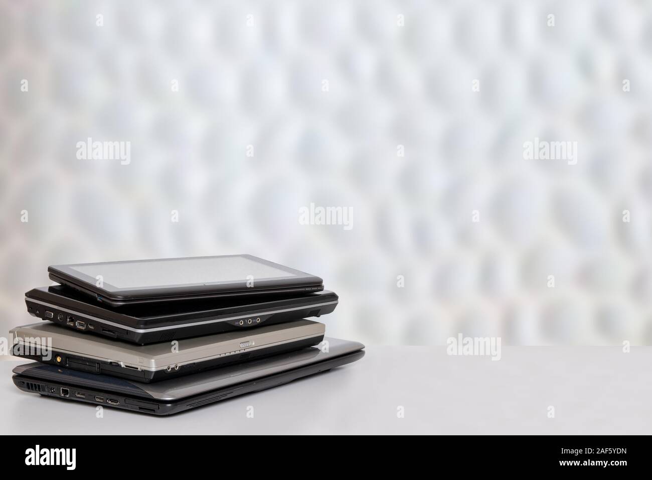Stack of laptop computers. A pile of computers on a bright table against abstract blurred white communication and technolgy texture background. Templa Stock Photo