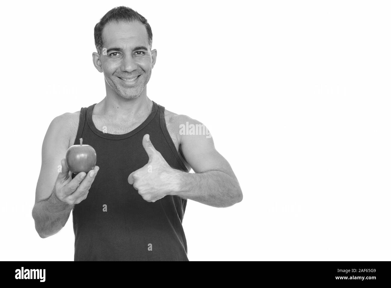 Mature happy Persian man holding red apple and giving thumb up getting ...