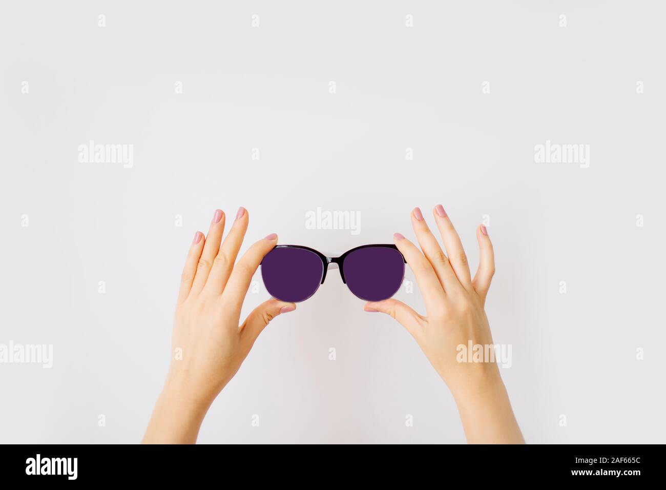 Female hands holding stylish sunglasses with dark purple lens isolated