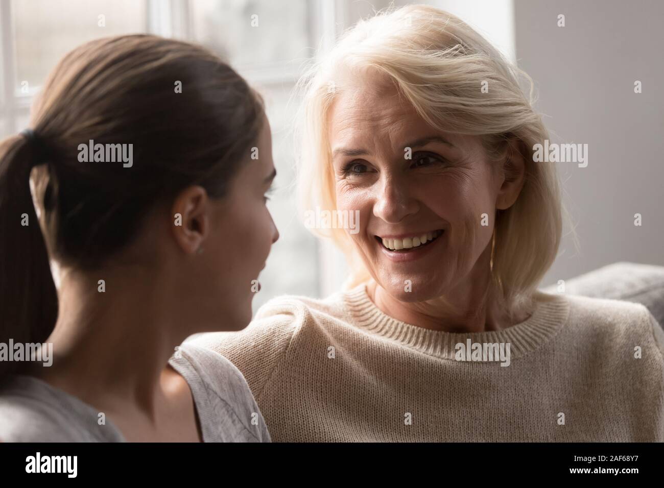Smiling elderly mother and adult daughter chat at home Stock Photo