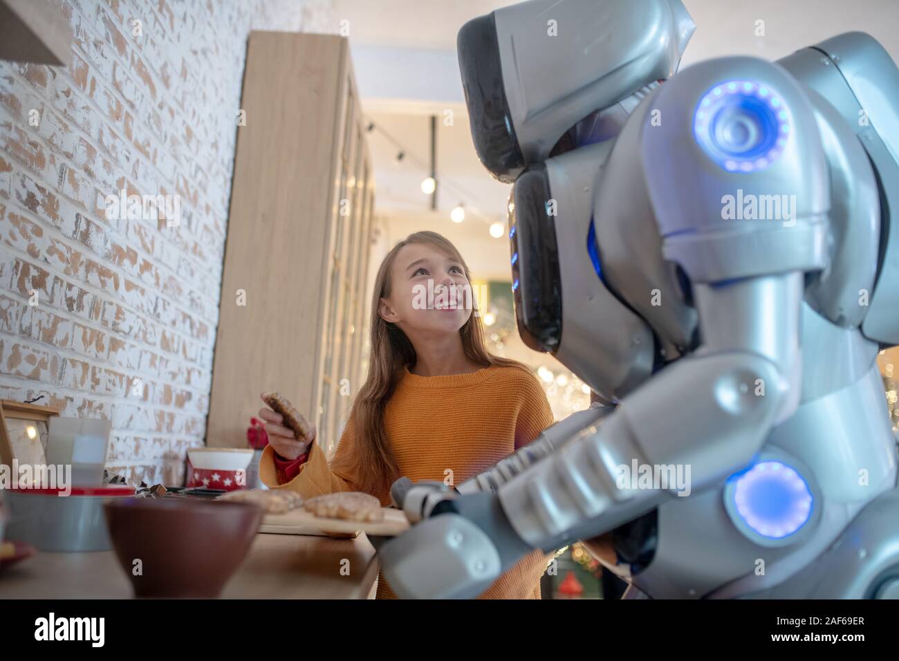 Pretty beaming girl looking at house robot Stock Photo - Alamy