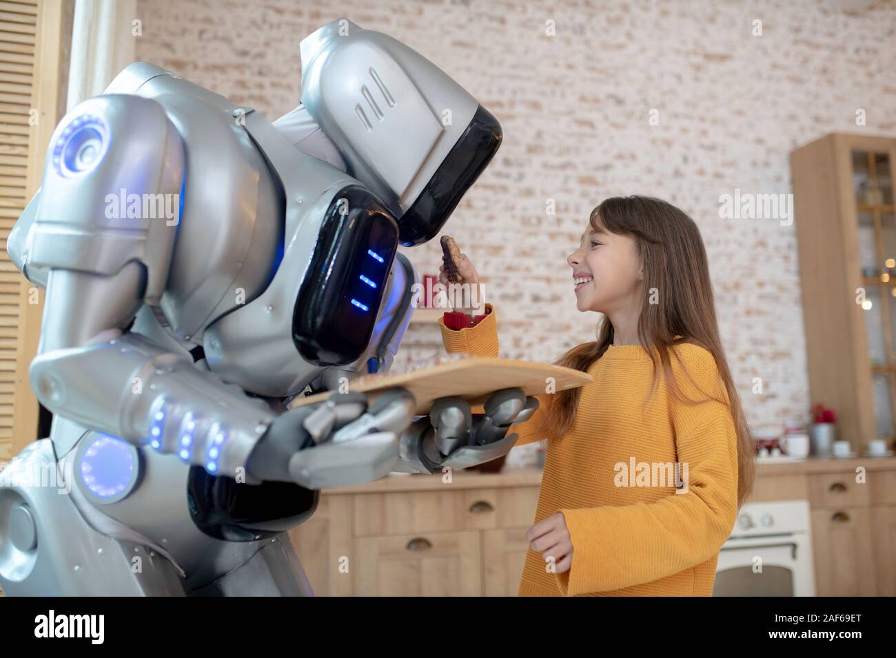 Cute long-haired girl feeding the house robot Stock Photo - Alamy