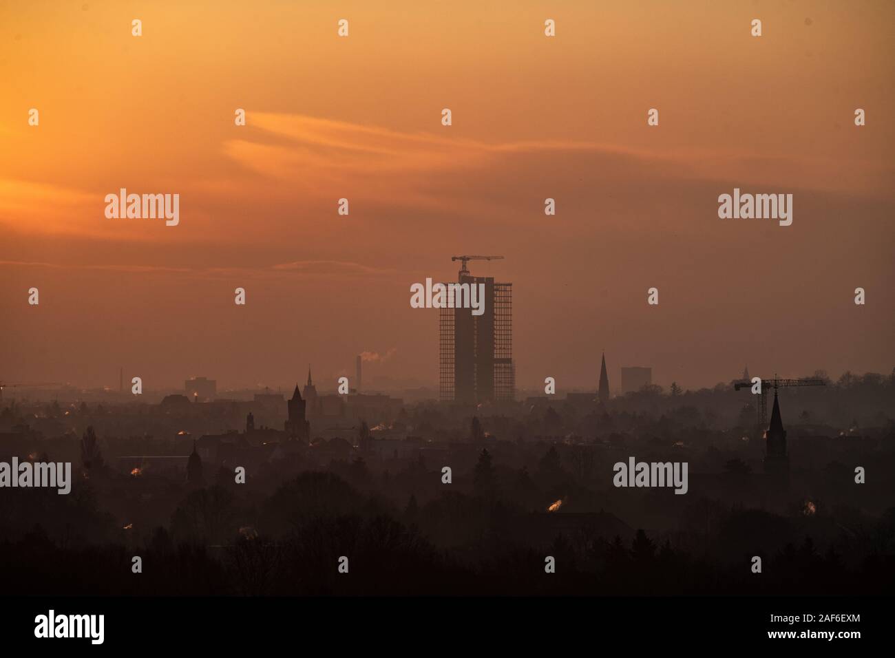 13 December 2019, Berlin: The Steglitzer Kreisel building complex can only be recognised as a silhouette in the light of the rising sun. The tower, which is over 100 metres high, is currently being completely renovated. Photo: Paul Zinken/dpa Stock Photo