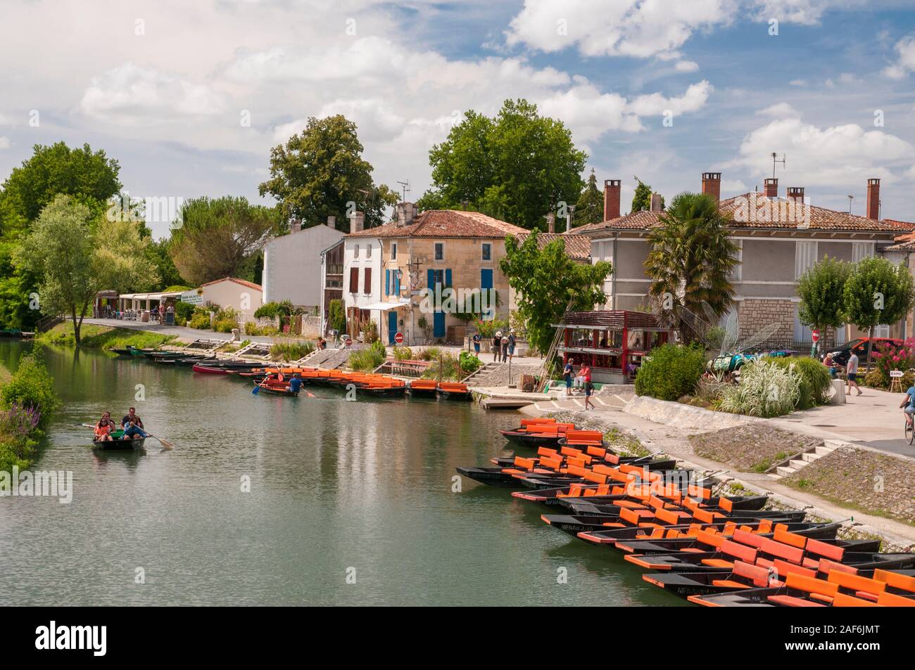 Orange tourist pleasure boats on the Sevre Niortaise river in the picturesque town of Coulon, Deux-Sevres (79) in the Marais Poitevin, France Stock Photo