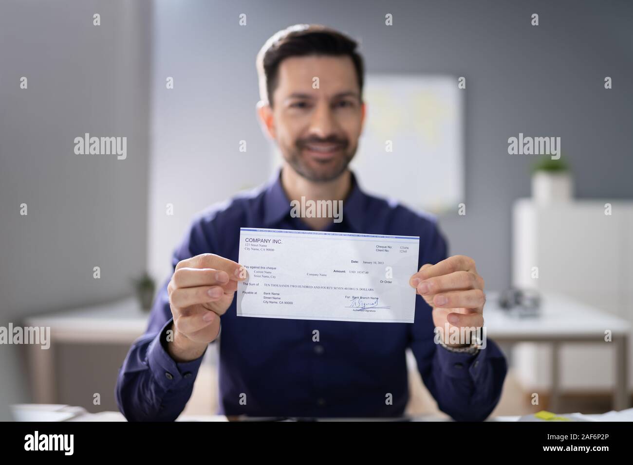 Portrait Of Mid Age Happy Businessman Offering Cheque Stock Photo