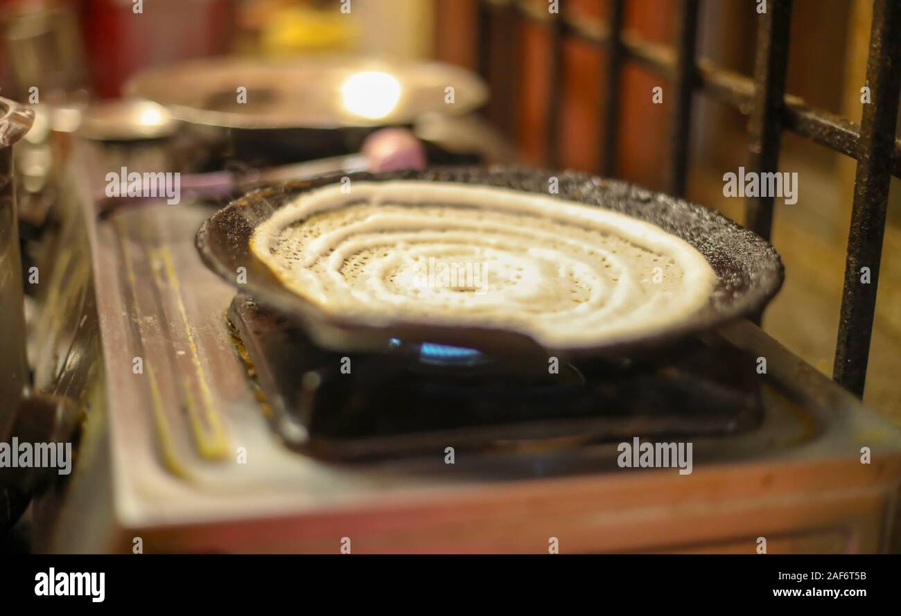 Dosa Indian food. women cooking or making of Dosa in kitchen, India