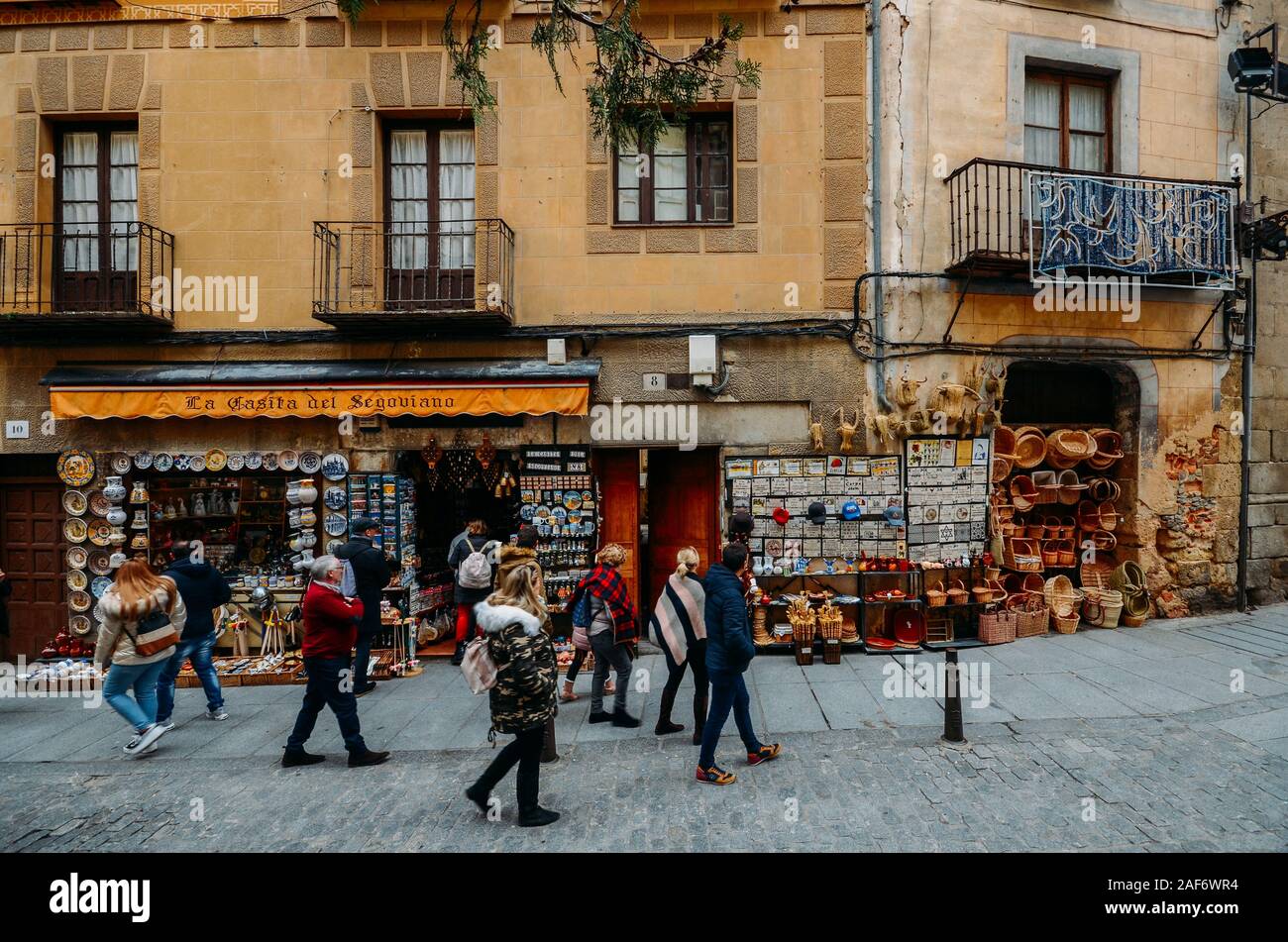Segovia, Spain - Dec 8, 2019: Tourists walk along a street lined with souvenir shops in the historic centre of Segovia, Spain Stock Photo