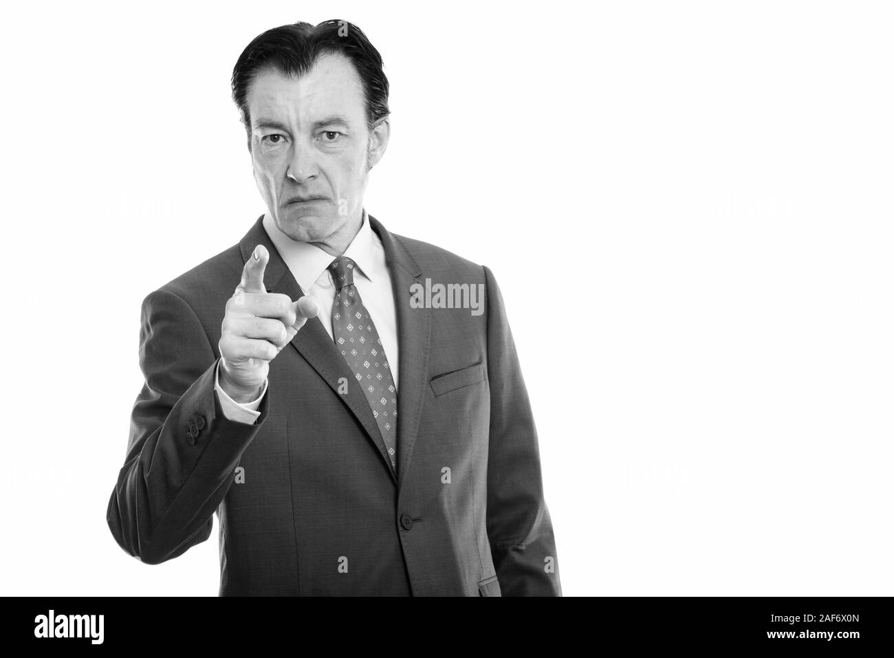 Studio shot of mature angry businessman pointing at camera Stock Photo