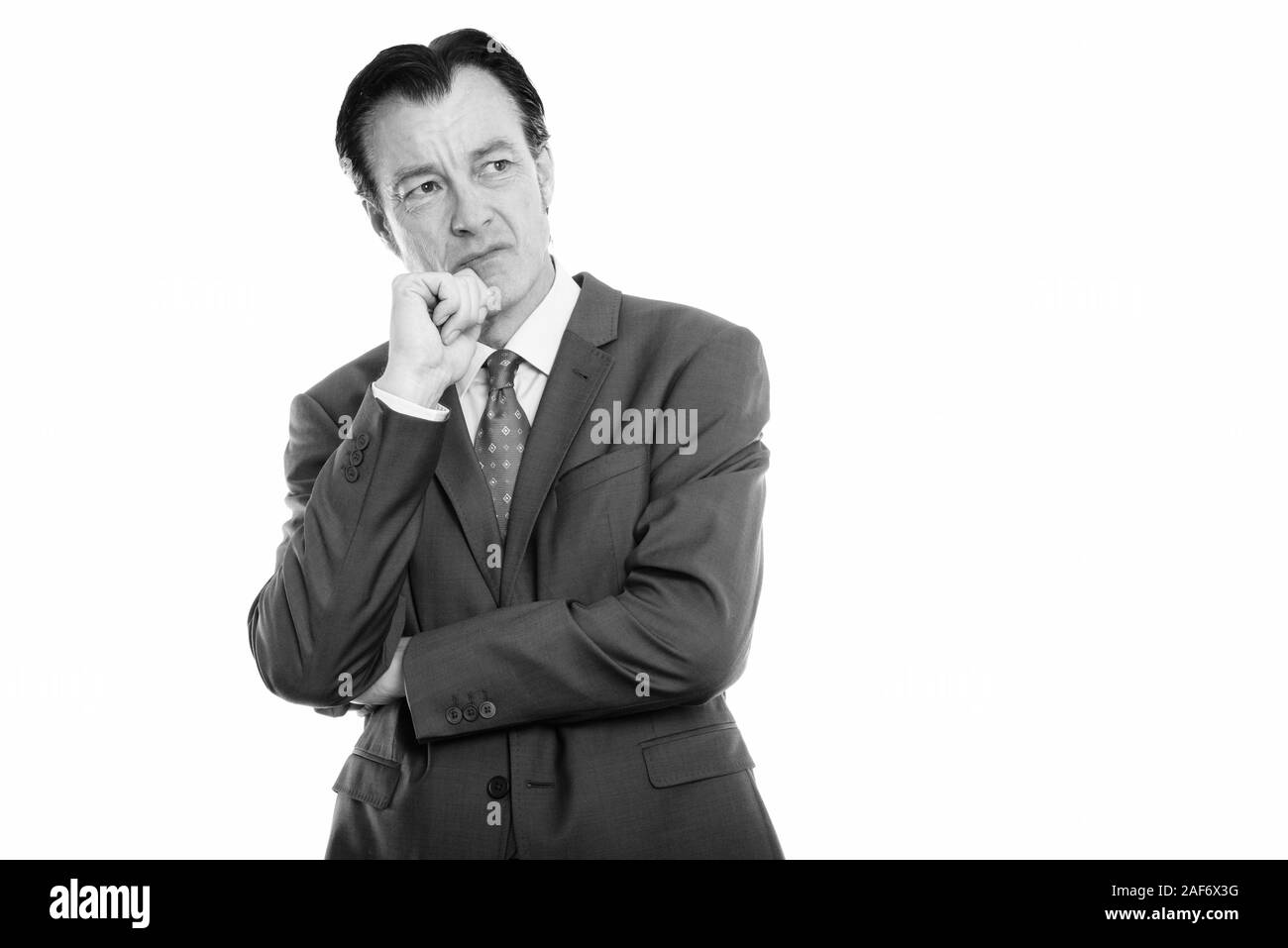 Studio shot of mature angry businessman thinking while looking up Stock Photo