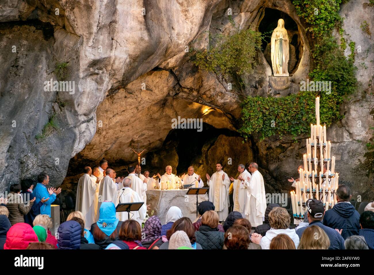 Praying at a morning mass or service, Grotte de Massabielle / Grotto of Massabielle, Sanctuary of Our Lady of Lourdes, Lourdes, Pyrenees, France Stock Photo