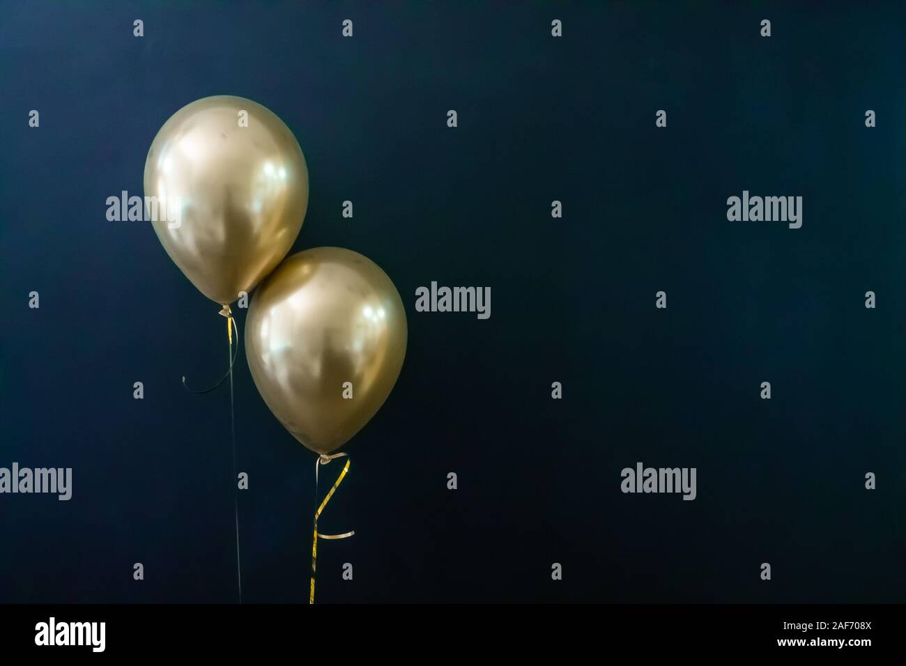 two golden balloons on a dark background. Holiday Concept, Postcard Stock Photo