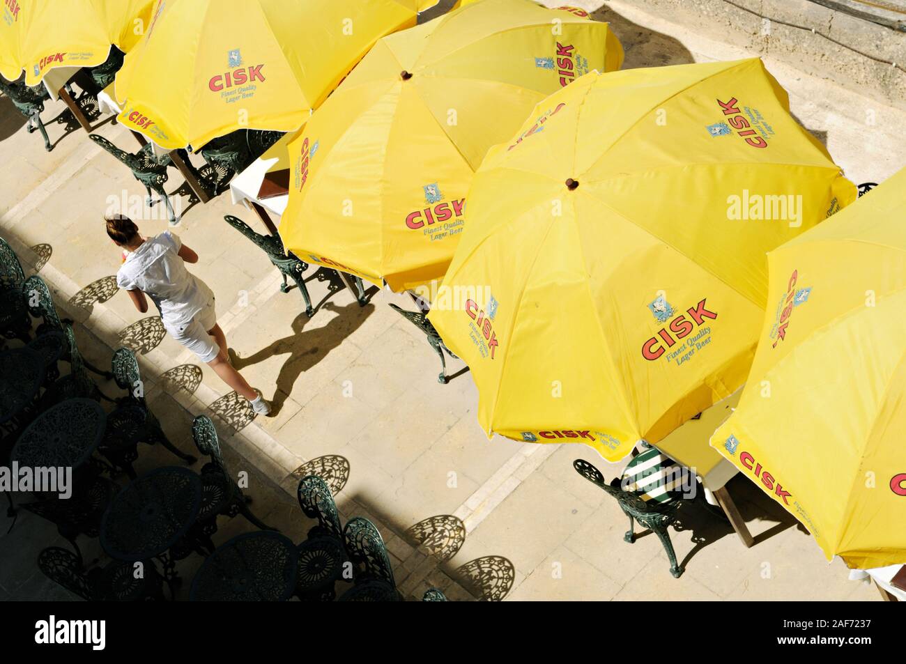 CISK yellow parasols and waitress on a terrace in Valletta, Malta Stock Photo