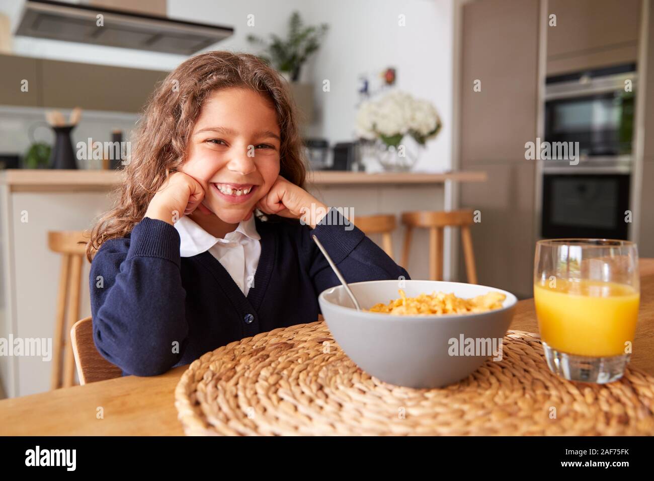 Portrait Of Girl Wearing Uniform In Kitchen Eating Breakfast Cereal
