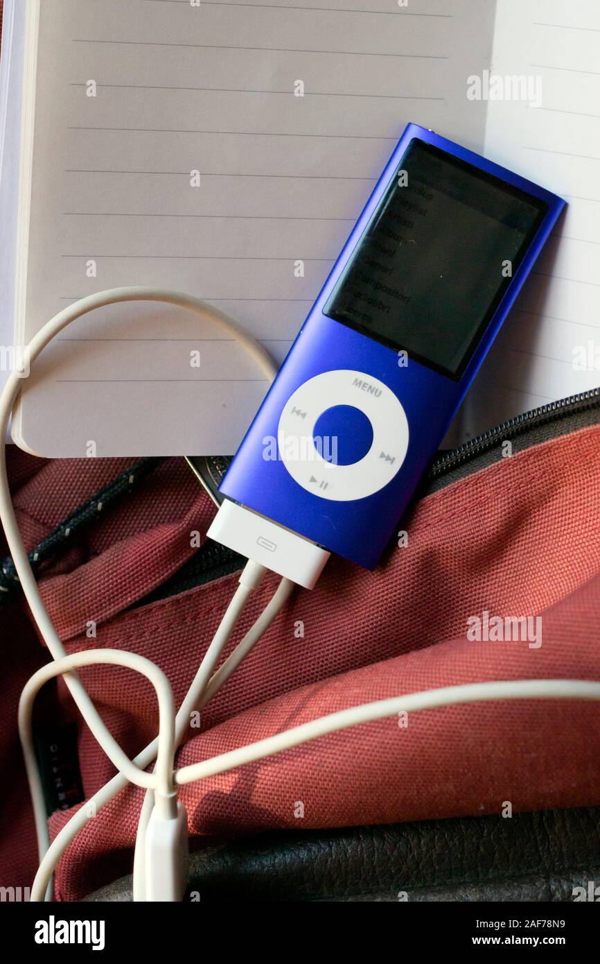 Milan, Italy - June 4, 2019. Blue Apple iPod Nano 8Gb Music Player with charger cable attached on notebook and schoolbag background Stock Photo