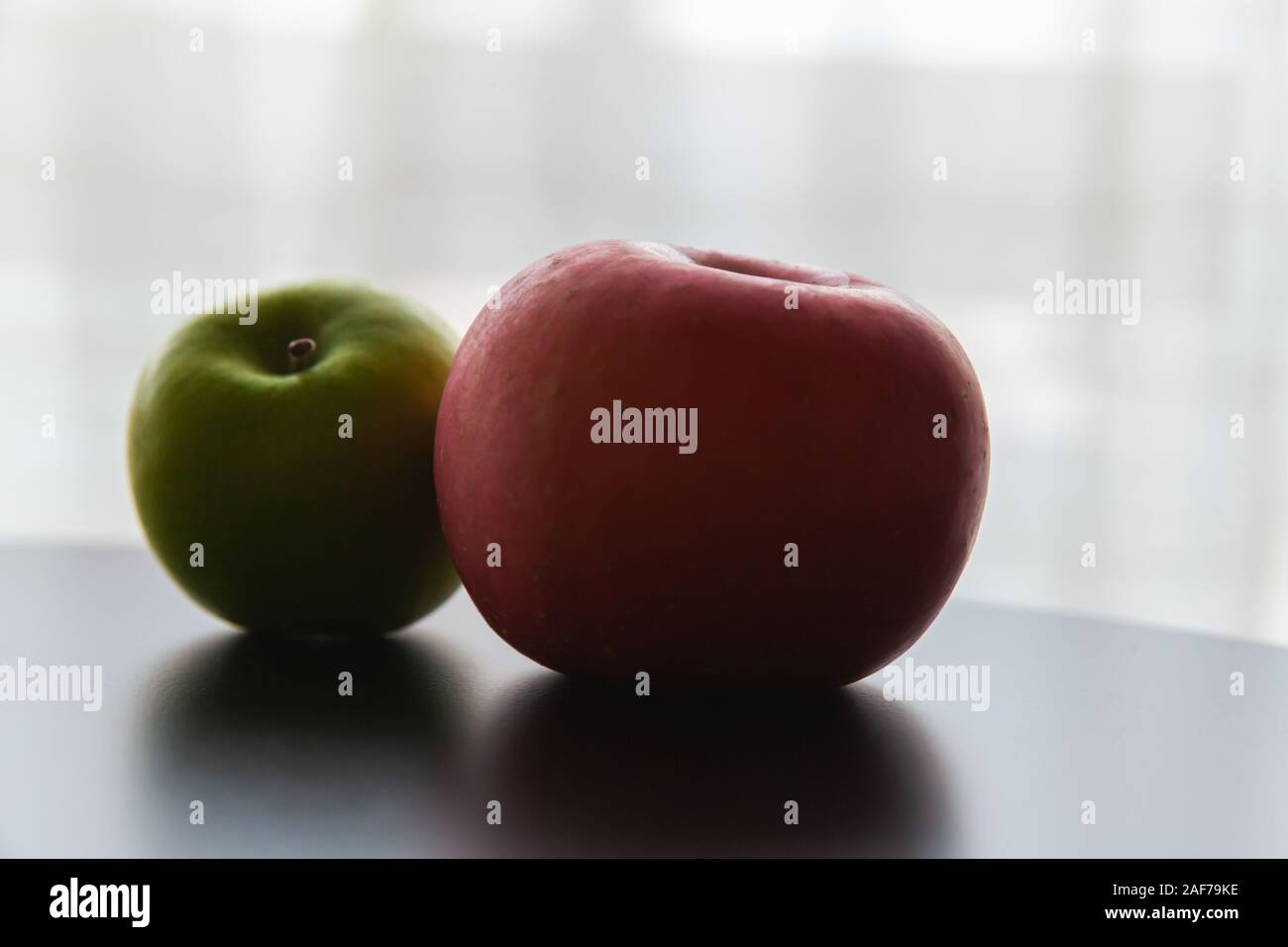 Two apples green and red lay on a black desk. Close up low-key photo with soft selective focus Stock Photo