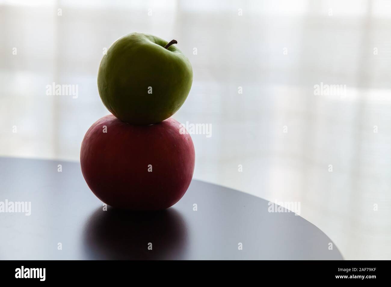 Two apples green and red lay on a black table. Close up low-key photo with soft selective focus Stock Photo