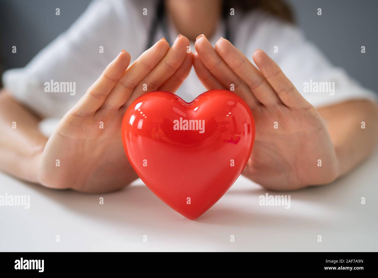 Midsection Of Female Doctor Protecting Red Heart At Desk In Office ...