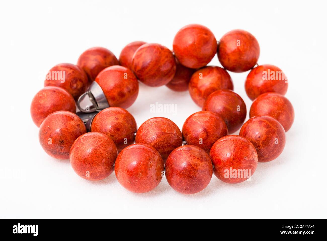 tangled necklace from polished red coral balls on white paper background Stock Photo