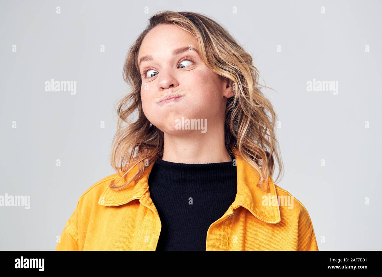 Head And Shoulders Studio Shot Of Woman Pulling Faces And Smiling At Camera Stock Photo