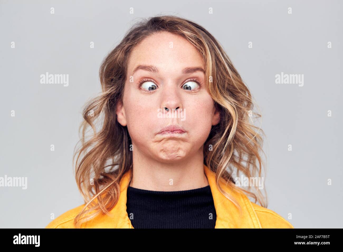 Head And Shoulders Studio Shot Of Woman Pulling Faces And Smiling At Camera Stock Photo