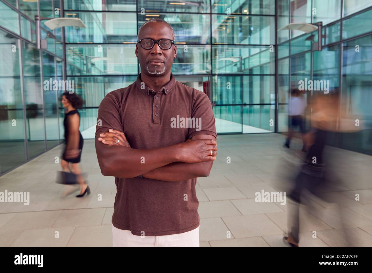 Portrait Of Mature Businessman With Crossed Arms Standing In Lobby Of ...