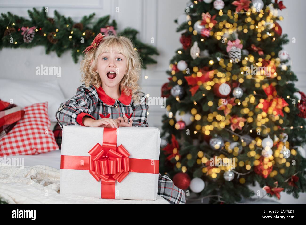 Happy excited girl child holding christmas gift box. Child giving a
