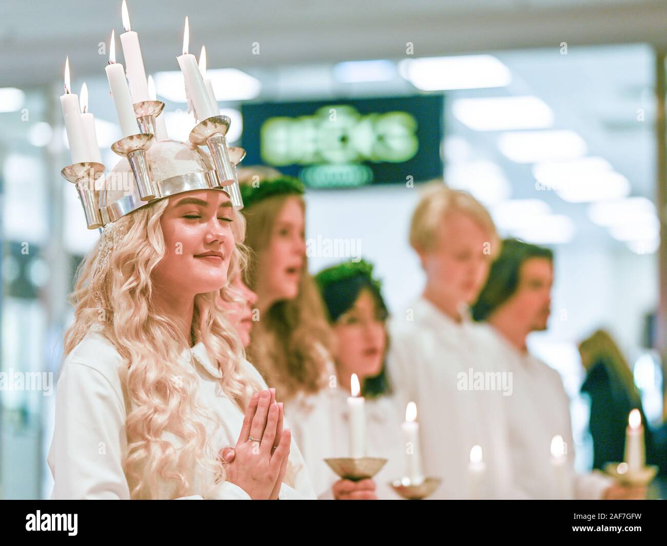 Traditional celebration of Saint Lucy in Sweden. Norrkoping’s Lucia 2019 Izabella Swartz singing carols in shopping mall Linden. Stock Photo