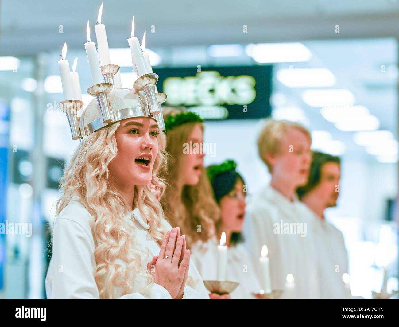 Traditional celebration of Saint Lucy in Sweden. Norrkoping’s Lucia 2019 Izabella Swartz singing carols in shopping mall Linden. Stock Photo